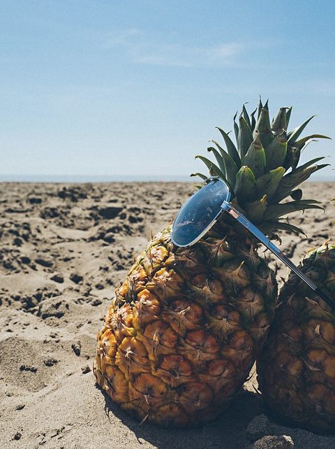 pineapples with sunglasses on the beach